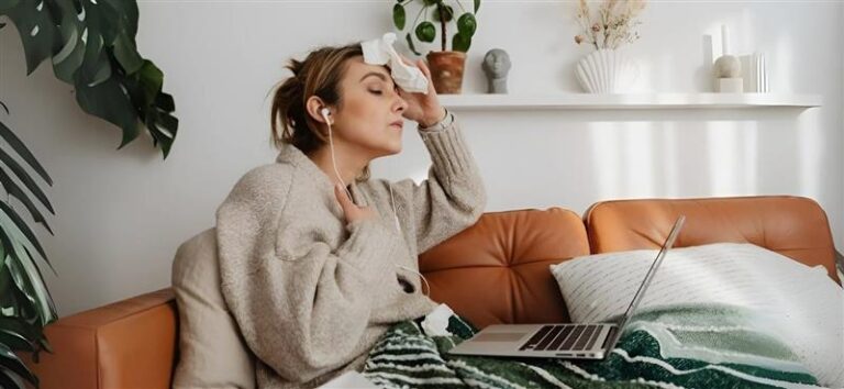 Woman Feeling Hot, Wiping Sweat While Sitting with a Laptop